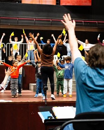 Children wave small yellow flags at a pOpera event of the Fondation EME.